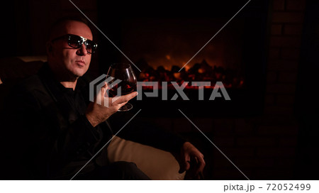 Mature man drinking cognac by the fireplace. Mature man drinking cognac by the fireplace. 72052499