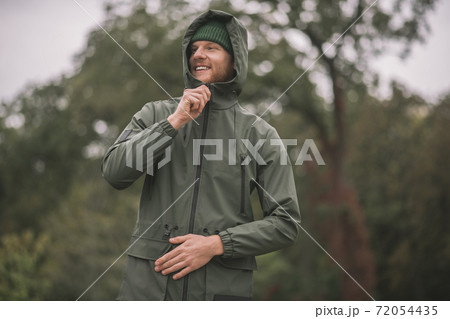 Young man in a green coat standing in the rain Young man in a green coat standing in the rain 72054435