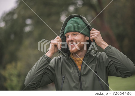 Young man in a green coat walking in the rain Young man in a green coat walking in the rain 72054436