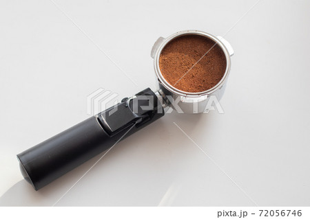 Ground coffee into a portafilter for preparing. Professional barista tool Ground coffee into a portafilter for preparing. Professional barista tool 72056746