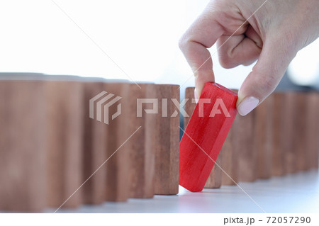 Female hand pulling out red wooden block from line closeup Female hand pulling out red wooden block from line closeup 72057290