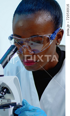 Close up of black woman looking in microscope 72058916