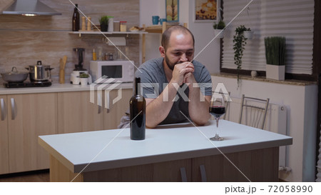 Sad husband drinking in the kitchen Sad husband drinking in the kitchen 72058990