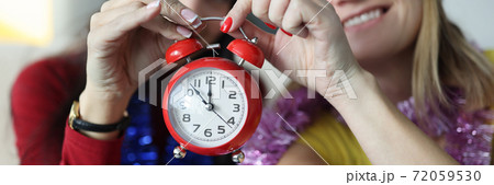 Two women in santa claus hats hold red alarm clock. Two women in santa claus hats hold red alarm clock. 72059530