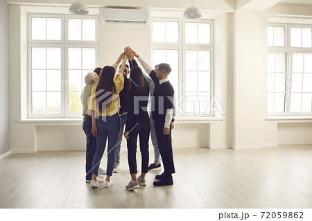 Group of diverse people standing in circle in office space and joining their hands Group of diverse people standing in circle in office space and joining their hands 72059862