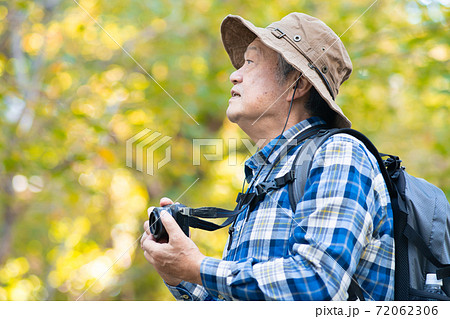 ハイキングで写真撮影をするシニア男性 72062306