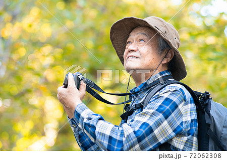 ハイキングで写真撮影をするシニア男性 72062308