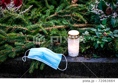 Victim of Coronavirus Covid 19, conceptual photo with protective medical mask on a stone tomb in the cemetery. Death from Covid 19 Victim of Coronavirus Covid 19, conceptual photo with protective medical mask on a stone tomb in the cemetery. Death from Covid 19 72063664