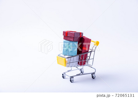Miniature cart with gifts on a white background. Holidays shopping concept. Close-up. 72065131
