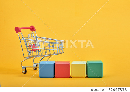 empty wooden cubes mockup style, copy space with shopping trolleys on yellow background. Colourful blocks template for creative design, place for text 72067338