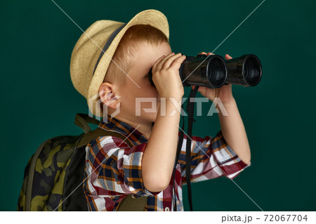 Little boy tourist with backpack looking through a binoculars. Little boy tourist with backpack looking through a binoculars. 72067704
