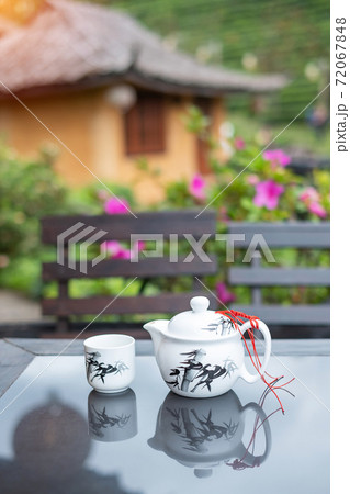 teapot and hot tea to cup on wood table against tea garden view background in the morning, Ban Rak Thai village, Mae Hong Son province, Thailand 72067848