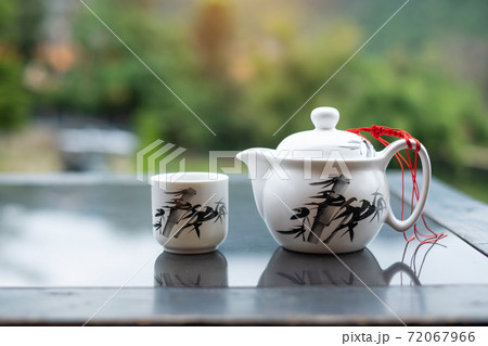 teapot and hot tea to cup on wood table against tea garden view background in the morning, Ban Rak Thai village, Mae Hong Son province, Thailand teapot and hot tea to cup on wood table against tea garden view background in the morning, Ban Rak Thai village, Mae Hong Son province, Thailand 72067966