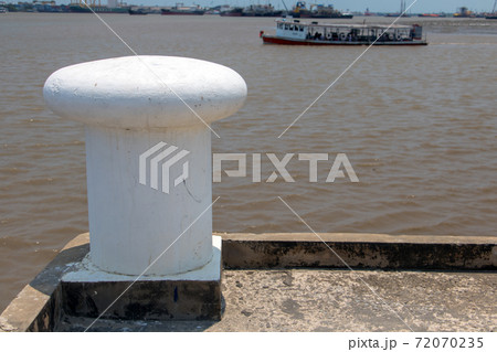 A shore with a white bollard and ferry on background. 72070235