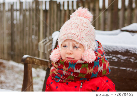 Winter outdoor portrait of adorable dreamy baby girl in knitted hat and scarf. Winter outdoor portrait of adorable dreamy baby girl in knitted hat and scarf. 72070455