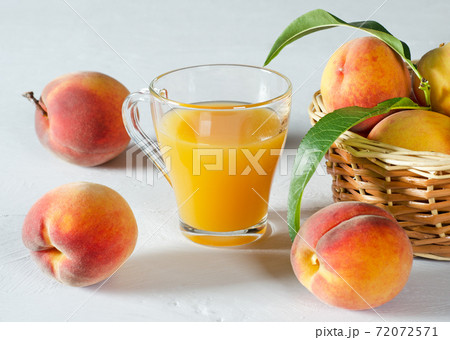 A glass with peach juice and ripe peaches. 72072571