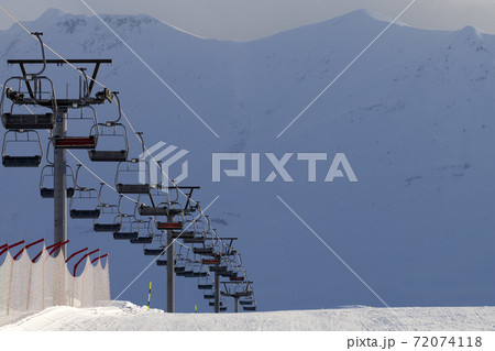 Snowy ski slope and chair lift on high mountains at winter evening Snowy ski slope and chair lift on high mountains at winter evening 72074118