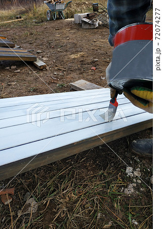 A man paints a white board with a paint brush 72074277