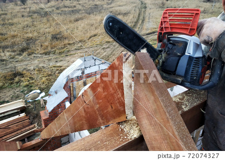 The builder saws on the roof of the chainsaw. Roof rafters. 72074327
