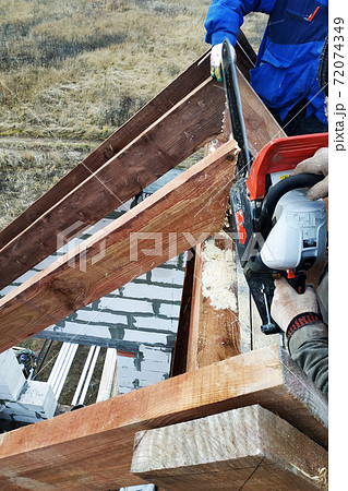 Workers cut the rafters on the roof of the chainsaw house Workers cut the rafters on the roof of the chainsaw house 72074349