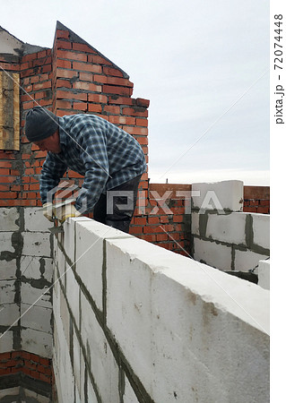 With the help of a glutinous solution, the worker builds a wall of gas blocks 72074448