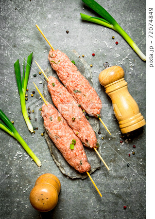 Raw kebabs on Wooden skewers with green onions. 72074849
