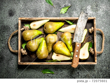 Ripe pears on a tray with an old knife. Ripe pears on a tray with an old knife. 72075601