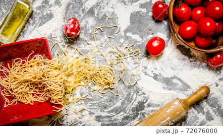 Noodles with tomatoes in a cup and rolling pin. 72076000