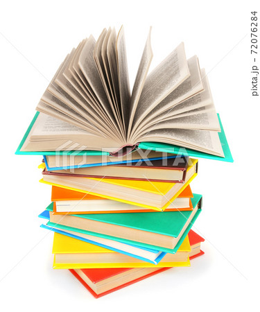 The open book on a pile of multi-coloured books. 72076284