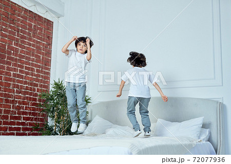 Jump higher. Happy latin boys, little brothers having fun together, jumping on the bed at home 72077936