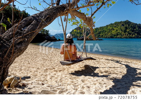 Young woman in wooden swing on the beach Young woman in wooden swing on the beach 72078755