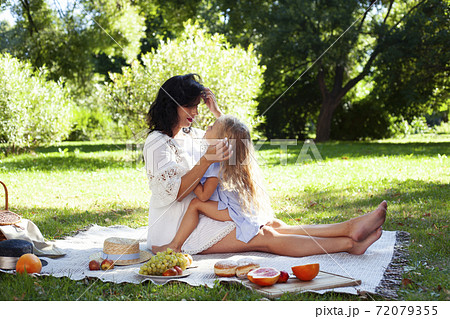 young pretty pregnant brunette woman having fun with her daughter on picnic on green grass in park, lifestyle people concept 72079355