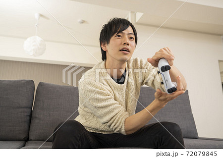 最新テレビゲーム機に夢中になる男性/プレステ/リビング 72079845