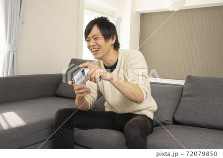 最新テレビゲーム機に夢中になる男性/プレステ/リビング 72079850