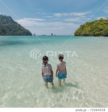 Two asian child girls standing and playing in the sea and enjoying with beautiful nature together with fun. Summer holidays and travel concept. Travelling in Thailand. 72084038