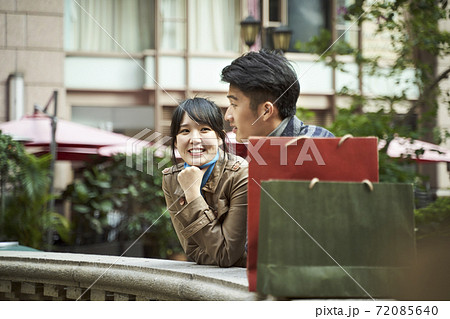 happy young asian couple relaxing chatting outdoors happy young asian couple relaxing chatting outdoors 72085640