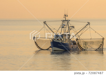 Fishing trawler with trawl nets at sunset, Buesum, North Sea, Schleswig-Holstein, Germany 72087487