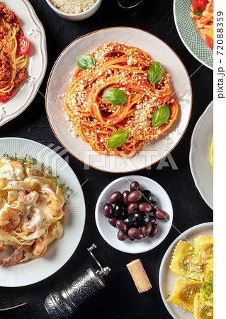 Italian food, shot from above on a black background. Spaghetti with basil, olives, wine cork, ravioli Italian food, shot from above on a black background. Spaghetti with basil, olives, wine cork, ravioli 72088359
