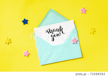 Thank You card in a teal blue envelope, shot from above on a yellow background Thank You card in a teal blue envelope, shot from above on a yellow background 72088362