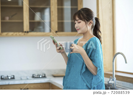 A young woman drinking coffee and using smartphone 72088539