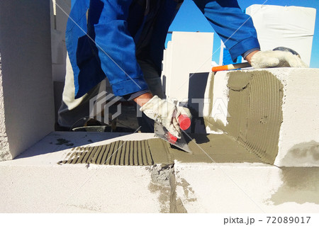 The master monitors the wall with gas blocks using glue and trowel 72089017