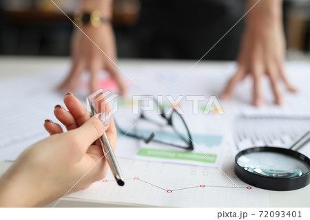 Hands hold pen on table are commercial charts and magnifying glass Hands hold pen on table are commercial charts and magnifying glass 72093401