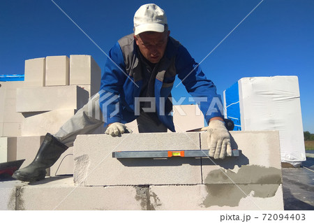 The worker checks the wall of gas blocks by a leveler The worker checks the wall of gas blocks by a leveler 72094403