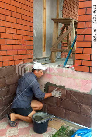 gluing a granite stone on the foundation of the building facing 72094621