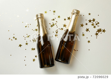 Champagne bottles and glitter on white background Champagne bottles and glitter on white background 72096029