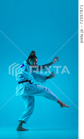 Young girl professional judoist isolated on blue studio background in neon light. Healthy lifestyle, sport concept. 72097871