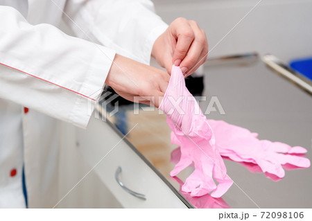 Doctor puts on gloves. 72098106