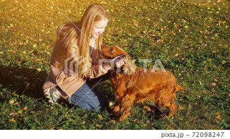 Teenager girl with long loose fair hair pets and kisses dog Teenager girl with long loose fair hair pets and kisses dog 72098247