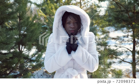 dark-skinned woman trembles with cold and warms hands dark-skinned woman trembles with cold and warms hands 72098371