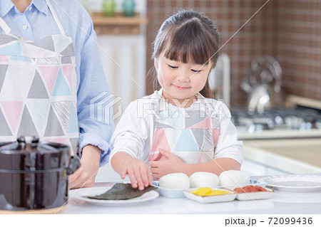 ファミリー おにぎりに海苔を巻く女の子の写真素材